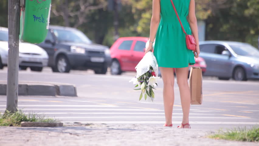 Leggy temptress in short skirt walking on the sidewalk